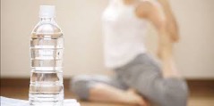 Water bottle in a yoga class, with woman stretching.