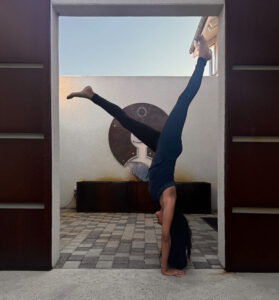 Yoga instructor practicing a hand stand in doorway.