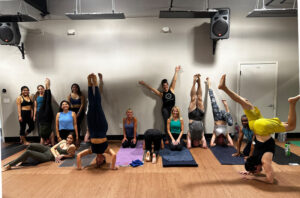 Fun picture of Samatone Yoga Inversion Class, with men and women smiling and doing various hand stands and other inversions.